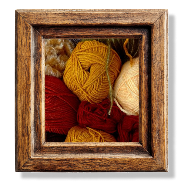 A close up of different balls of yarn in a wooden frame.