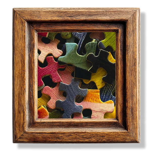 A close up of a pile of loose puzzle pieces in a wooden frame.