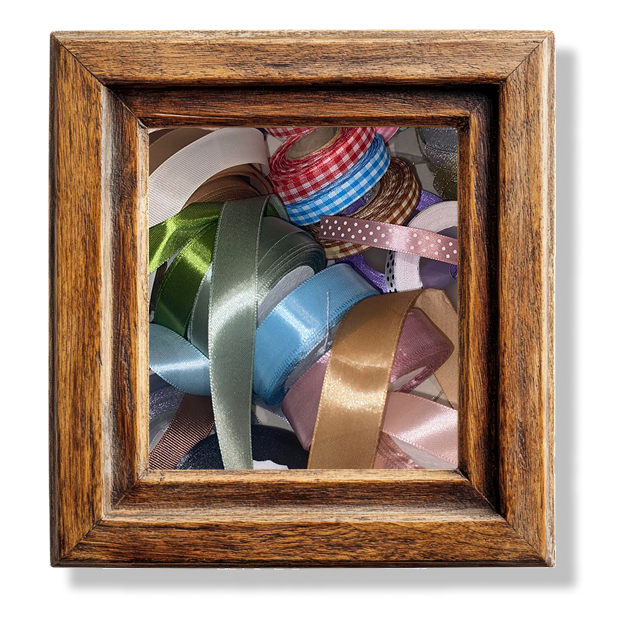 A pile of spools of ribbon in a wooden frame.