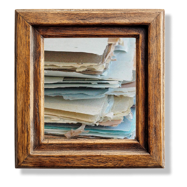 A stack of rough paper, all different shades of off-white in a wooden frame.