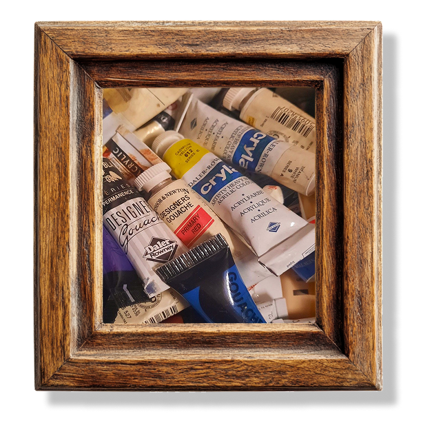 A close up of different tubes of acrylic paints in a wooden frame.