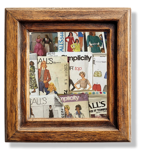 A pile of packaged paper sewing patterns in a wooden frame.